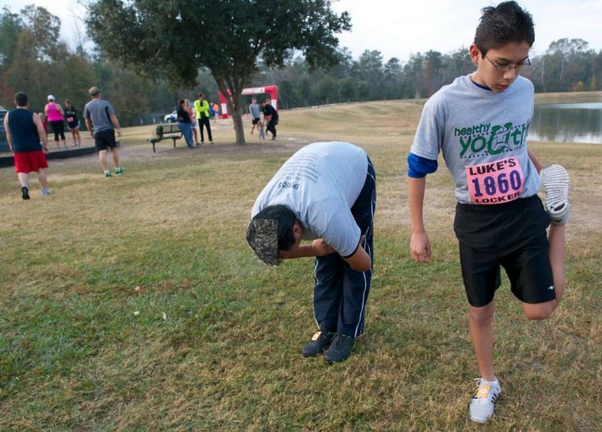Eduardo Linares, 13, with the Healthy Youth program, stretches alongside his father Octavio, left, before the start of the Eighth Annual Turkey Trot 5K Run at Carl Barton Jr. Park in Conroe Friday.