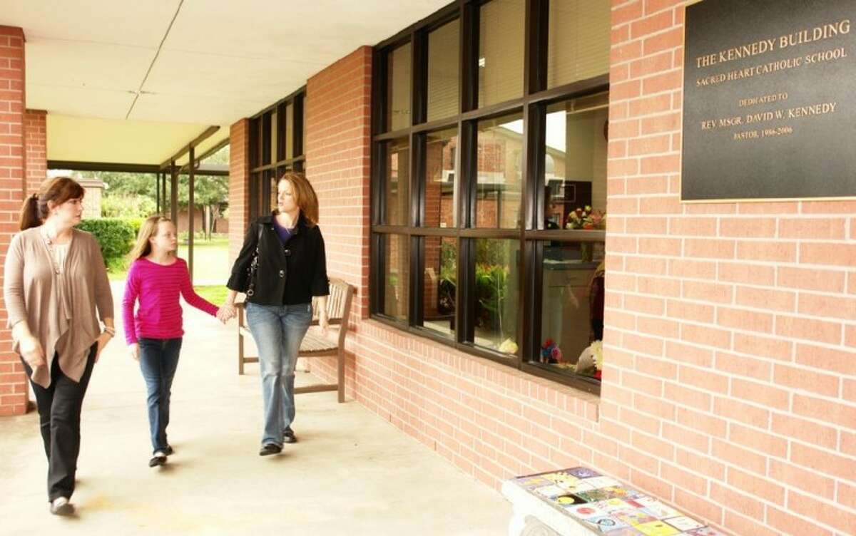 Stephanie Hill, Sacred Heart Catholic School board member, gives a campus tour to Marjorie Moreland and her third-grade daughter, Natalie, Thursday during an open house on campus as part of Catholic Schools Week.