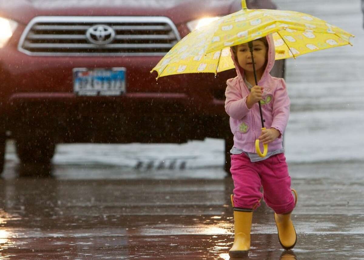 Lauren Davie, 2, of The Woodlands, holds an umbrella as she makes her way through the parking lot at the Panther Creek Shopping Center in The Woodlands. Heavy rains fell throughout the county Thursday.