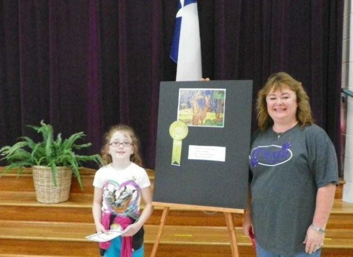 Turner Elementary student Loralee Downey displays the gold medal she won at the Rodeo Art Show to teacher Shannon Martin.
