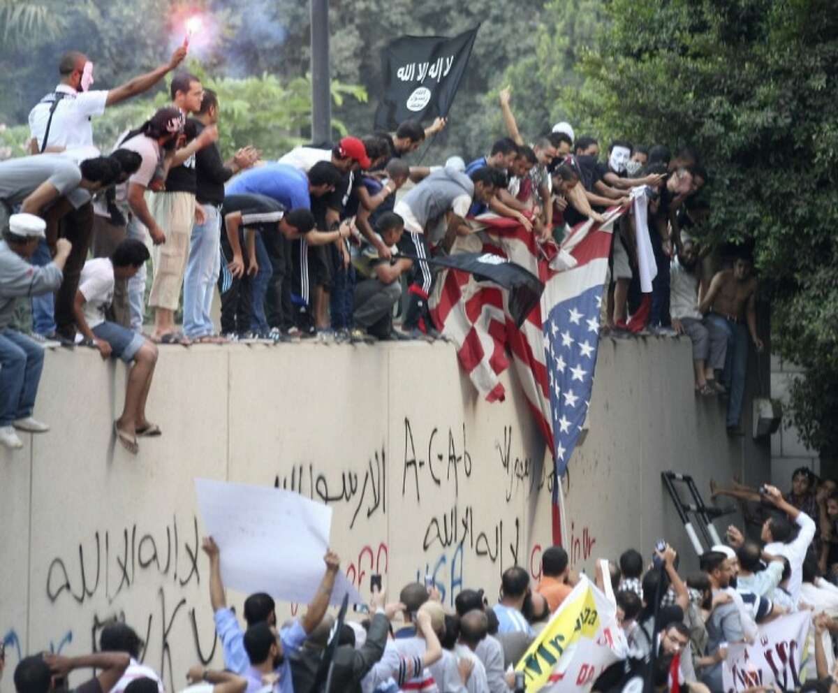 Protesters destroy an American flag pulled down from the U.S. embassy in Cairo, Egypt on Tuesday, the 11th anniversary of the Sept. 11, 2001 terror attacks on the U.S. Egyptian protesters, largely ultra conservative Islamists, climbed the walls of the U.S. embassy in Cairo, went into the courtyard and brought down the flag, replacing it with a black flag with Islamic inscription, in protest of a film deemed offensive of Islam.