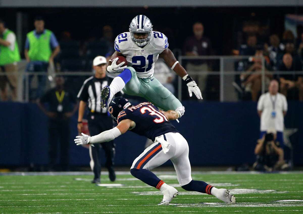 Cowboys running back Ezekiel Elliott leaps over the Bears' Chris Prosinski on his way to completing a 14-yard run in the second half of Sunday night's game.