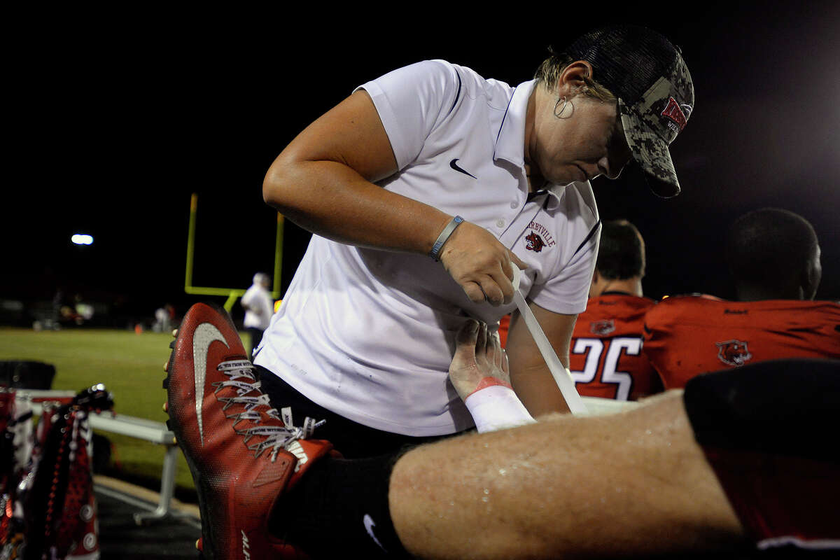 Kirbyville volunteer athletic trainer Larissa McMillon tapes a player's ankle during their game against Kountze at Wildcat Stadium on Friday night. The school does not have a full-time trainer. Photo taken Friday 9/23/16 Ryan Pelham/The Enterprise