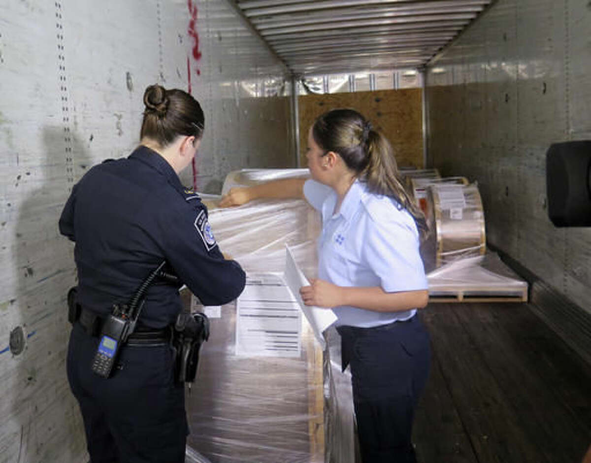 U.S. Customs and Border Protection officer Rachel McCormick, left, and Mexican customs officer Alejandra Galindo demonstrate how they would jointly inspect a cargo truck carrying goods from Mexico into the U.S. while at the Mariposa Inspection Facility at the Nogales Port of Entry in Arizona. Officials say the new program allowing Mexican officials to work with their U.S. counterparts has already reduced wait times by more than 75 percent. (AP Photo/Astrid Galv'n)
