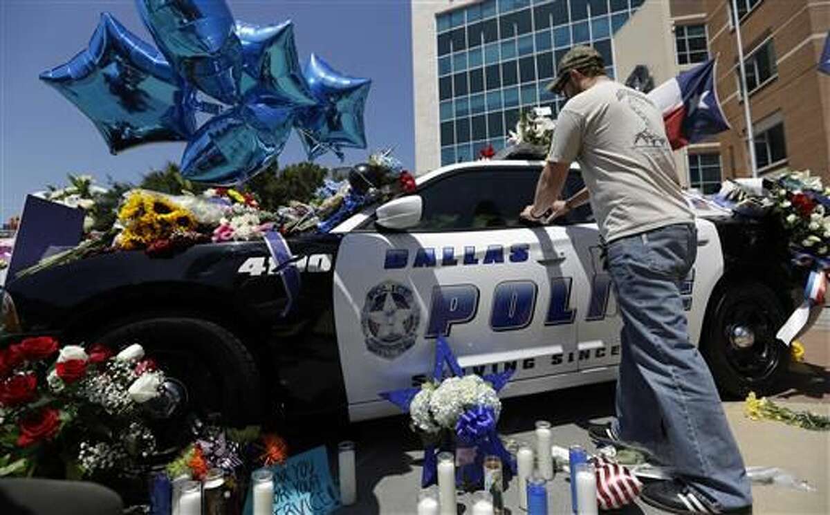 Michael O'Mahoney, a former police officer, places his patch on a make-shift memorial at the Dallas police headquarters, Friday, July 8, 2016, in Dallas. Five police officers are dead and several injured following a shooting in downtown Dallas Thursday night. (AP Photo/Eric Gay)