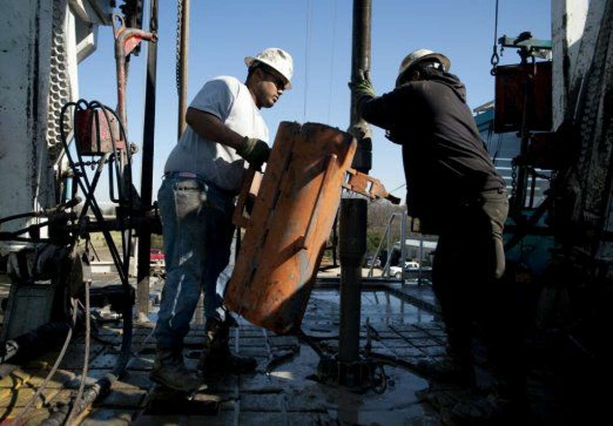     Toronto-based Trinidad Drilling Ltd. floorhands Julio Serrato, left, and Jaime Gonzalez work on the first drilling of the Reveille 1H Chesapeake Energy Corp. natural gas site in Fort Worth, Texas, U.S., on Monday, Nov. 23, 2009.