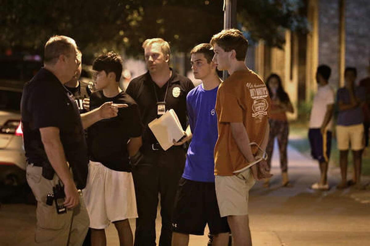 Daniel Hamilton Magee, second left, stands with Austin Police Department officers after being arrested late Sunday night, Sept. 11, 2016 in Austin, Texas. Magee, who isn't a UT student, was charged with aggravated assault after a security guard was injured in a shooting at the the Sigma Chi fraternity house. (Daulton Venglar/The Daily Texan via AP)