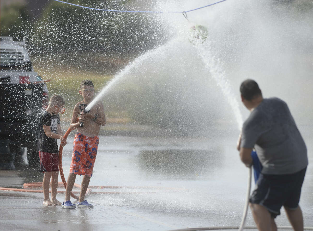 Event attendees compete to move a suspended ball with water hoses during the Midland Fire Department Wet 'n' Wild event on Wednesday, Aug. 10, 2016, at CJ Kelly Park. James Durbin/Reporter-Telegram
