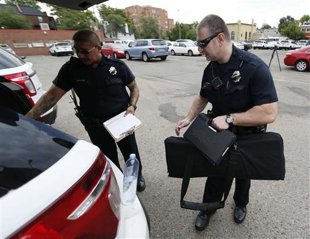 In this Monday, July 18, 2016, photograph, Denver Police Department officers head out to their patrol car after role call for the swing shift in District 6 in downtown Denver. After more than two decades of making officers patrol on their own, the city of Denver has revived two-officer patrols following the killings of officers in Dallas and Baton Rouge, La. (AP Photo/David Zalubowski)  