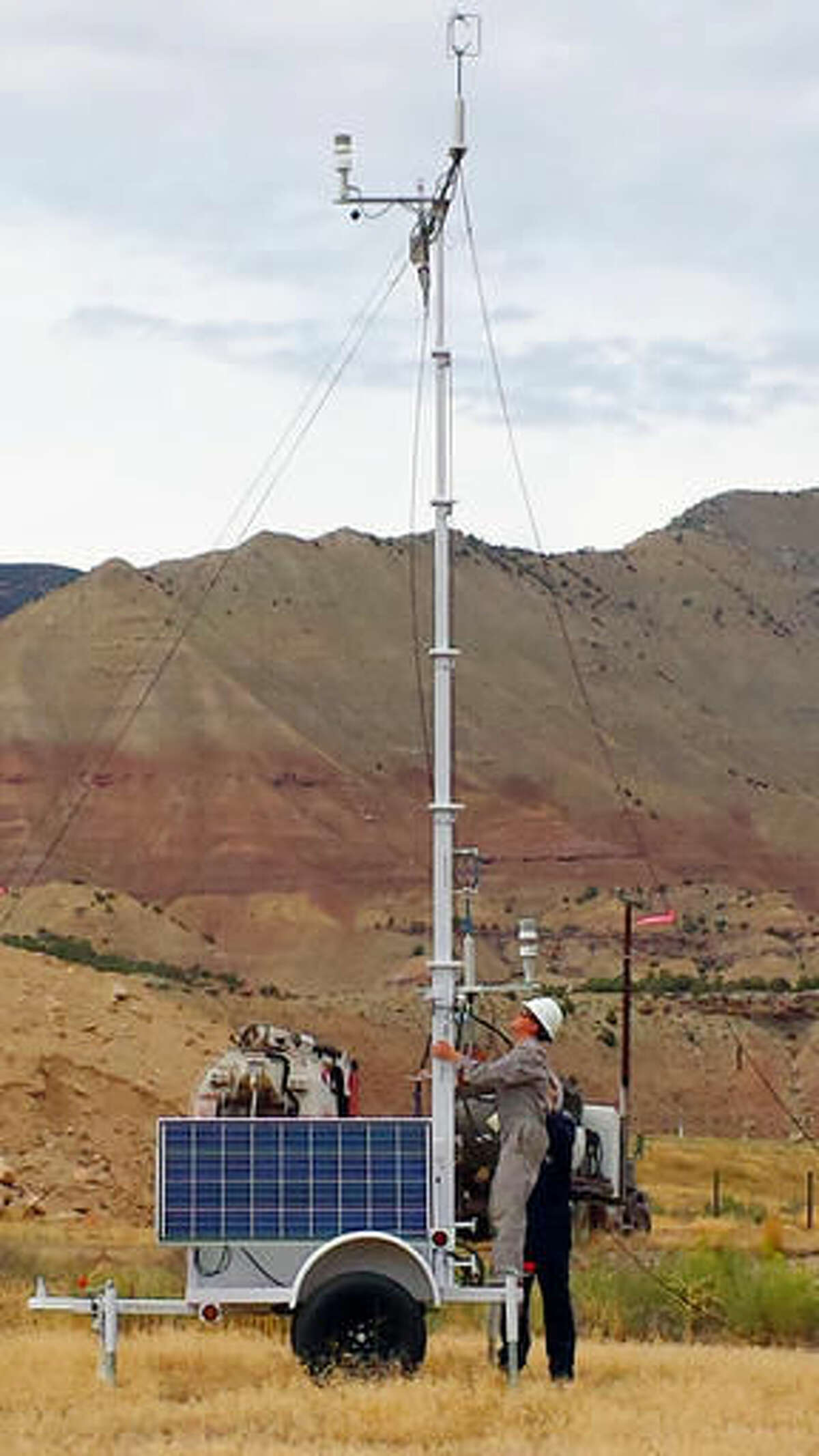 In this 2014 photo provided by Colorado State University, CSU research associate Kira Shonkwiler, front, and student Landan MacDonald, standing behind Shonkwiler, set up a weather station in Garfield County, Colo., as part of a study on air pollution from fracking wells. A study of air pollution from western Colorado fracking wells released Tuesday, June 14, 2016, found the highest rate of emissions came just after fracking was completed. (Arsineh Hecobian/Colorado State University via AP)