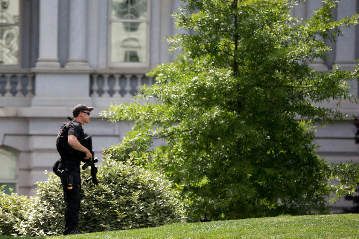 A Secret Service agent stands on the North Lawn of the White House Friday after the White House was placed on security alert after shooting on street outside.
