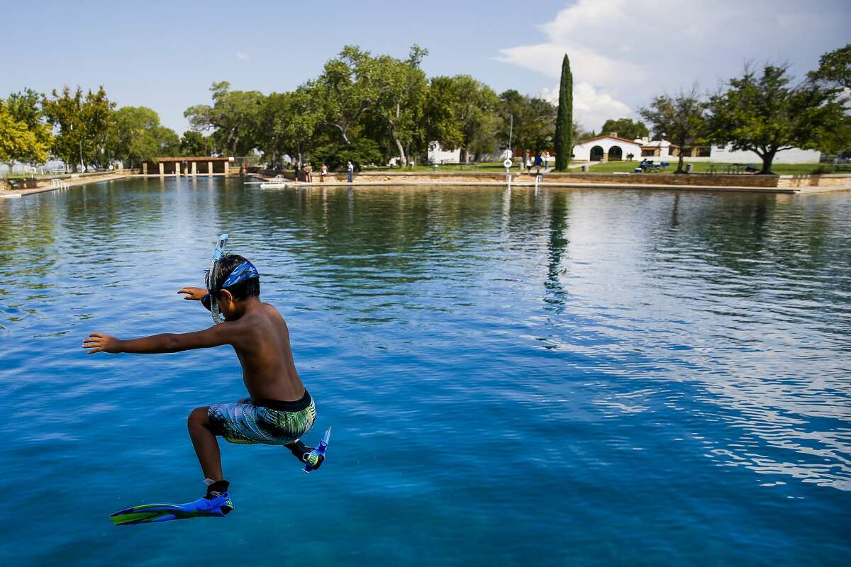 Dean Strong, 8, jumps into the crystal clear waters of the worlds largest spring-fed swimming pool in his snorkeling gear at Balmorhea State Park Friday, Sept. 16, 2016 four miles west of Balmorhea in Toyahvale, TX. Houston-based Apache Corporation recently announced the discovery of an estimated 15 billion barrels of oil and gas in the area and plans to drill and use hydraulic fracturing on the 350,000 acres surrounding the park. Apache has leased the mineral rights under the park and town, but has promised not to drill on or under either. Even with the promises, some residents worry that the drilling could affect the 15 million gallons of water that flow through the pool every day and impact the more than 200,000 visitors the pool attracts annually. ( Michael Ciaglo / Houston Chronicle )