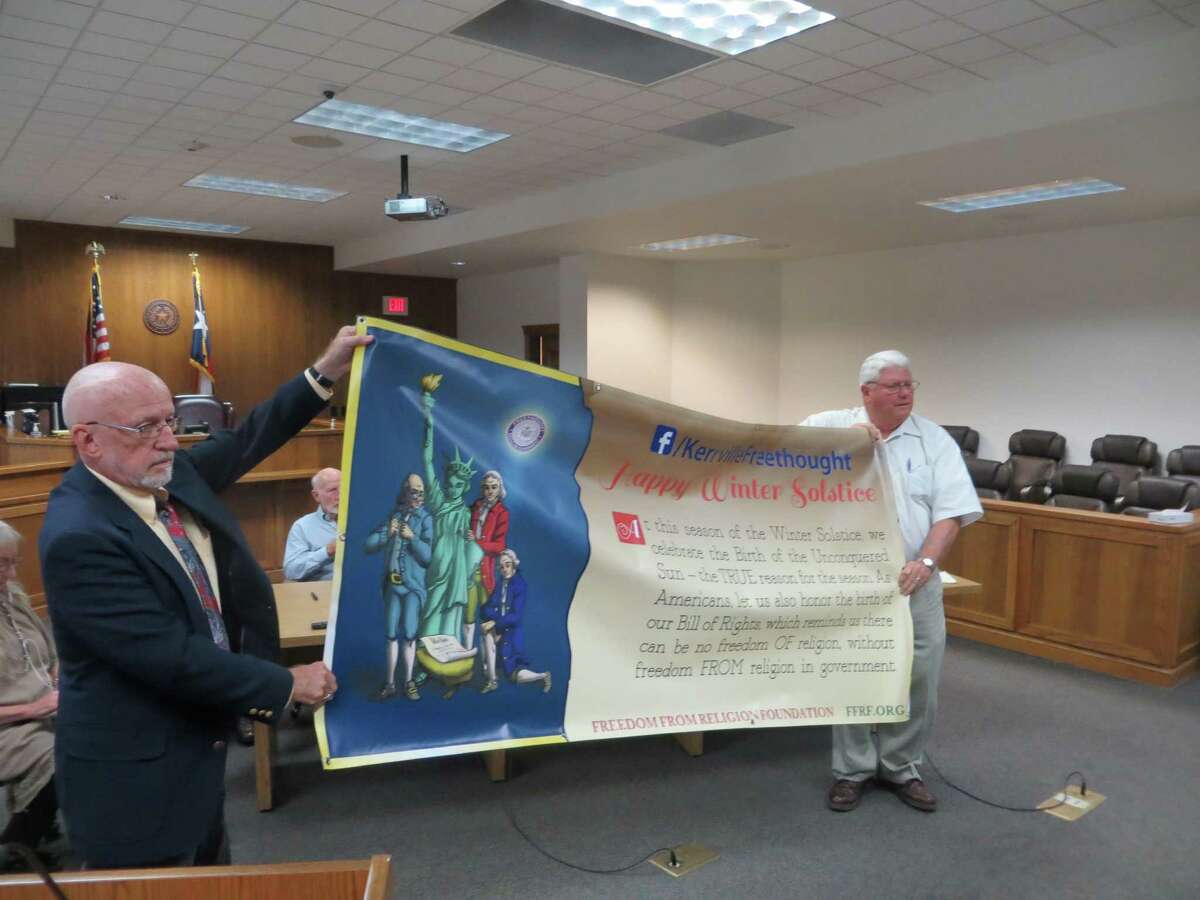 Kerrville Freethought representative David Whitsett (left) and Kerr County Judge Tom Pollard show what the banner that Whitsett wanted hung outside the courthouse looks like back in September, when county commissioners rejected the request. Another vote Monday had the same result, though Pollard this time voted in favor, predicting the county would lose in court.
