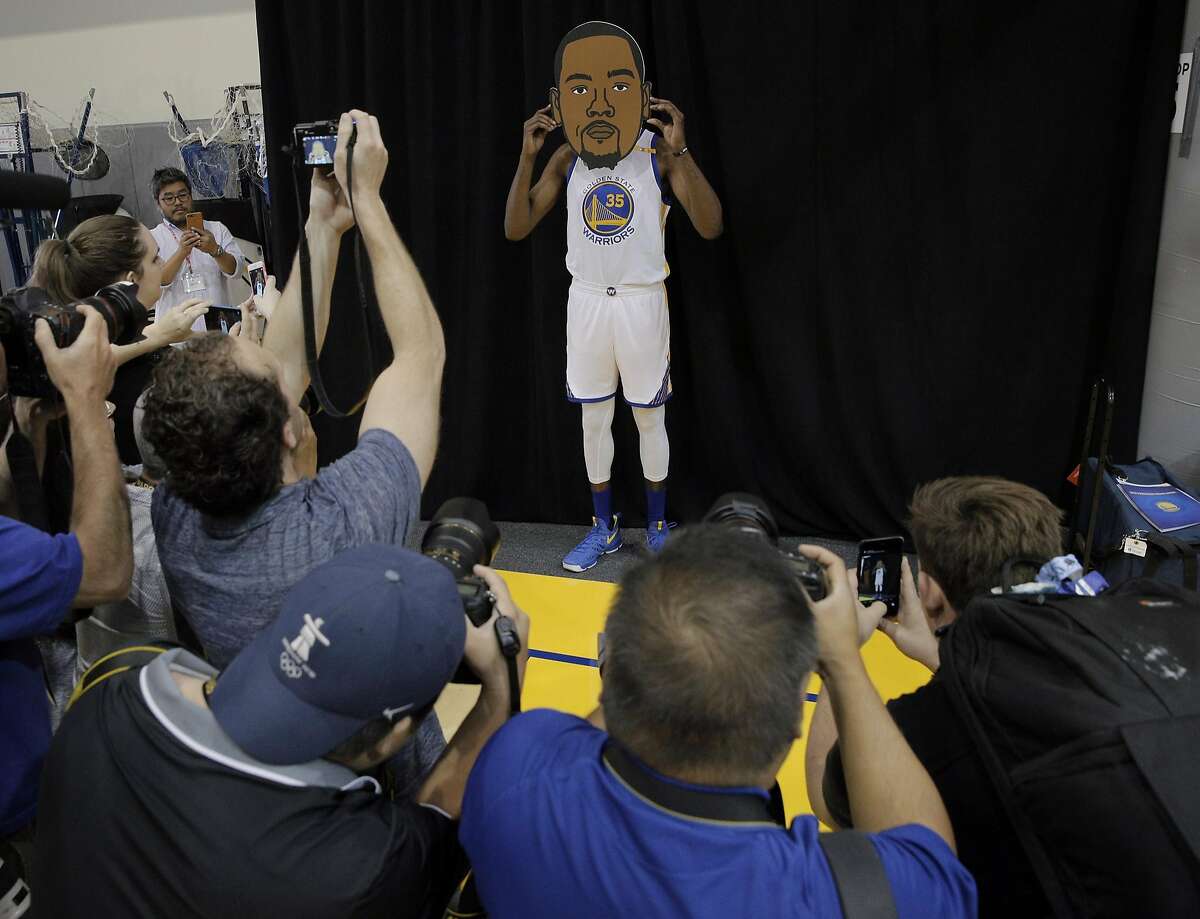 Kevin Durant (35) surrounded by photographers with a big emoji head during Warriors Media Day at their training facility in Oakland, Calif., on Monday, September 26, 2016.