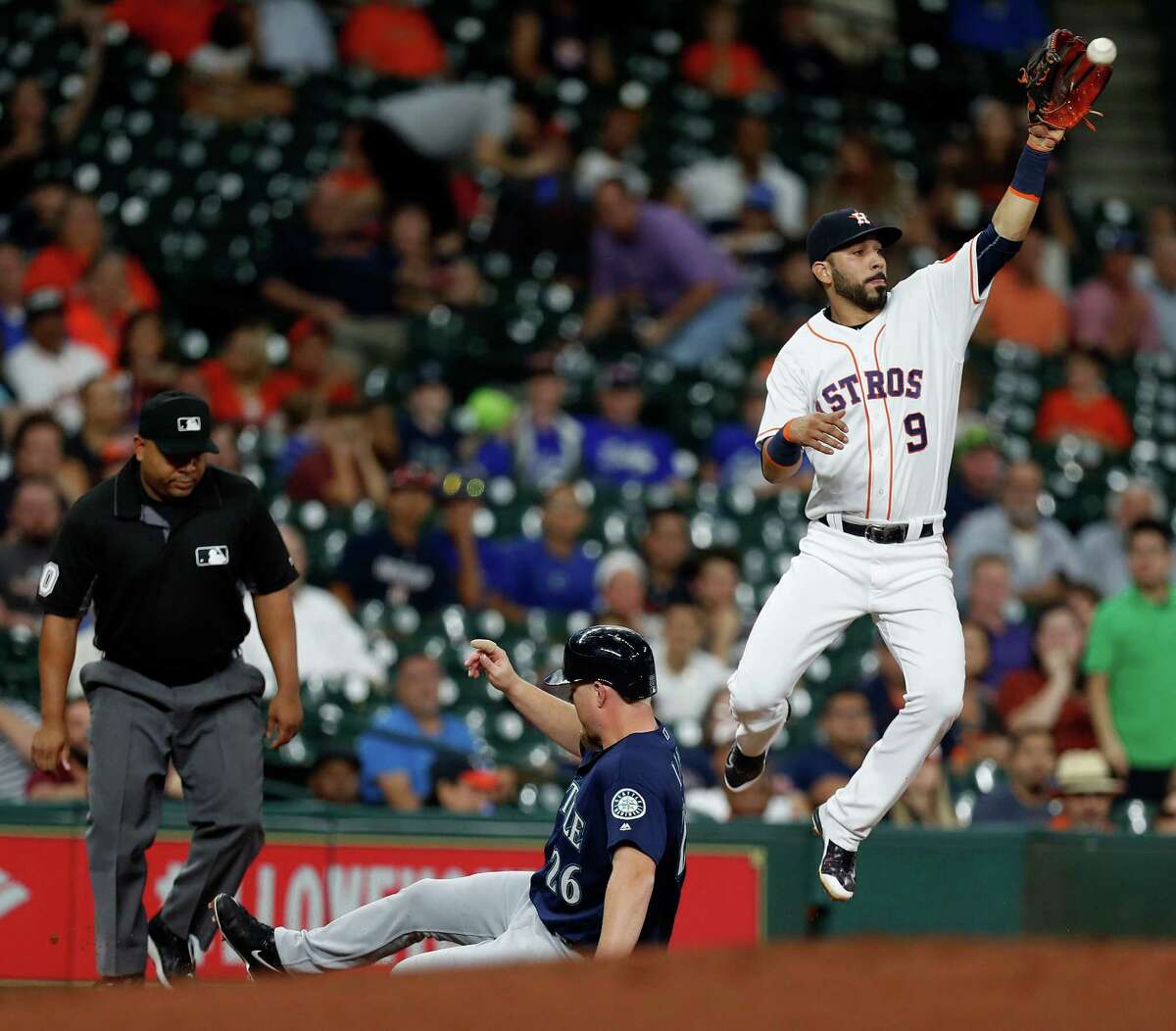 Houston Astros third baseman Marwin Gonzalez (9) tries to get the tag on Seattle Mariners Adam Lind (26) at third base in the second inning of an MLB game at Minute Maid Park, Monday, Sept. 26, 2016 in Houston.