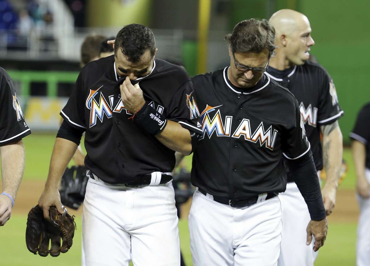 Miami Marlins' Martin Prado, left, walks off the field with manager Don Mattingly, right, after a baseball game against the New York Mets, Monday, Sept. 26, 2016, in Miami. The Marlins defeated the Mets 7-3. The Marlins pitcher Jose Fernandez was honored during the game. Fernandez was killed in a boating accident early Sunday. (AP Photo/Lynne Sladky)