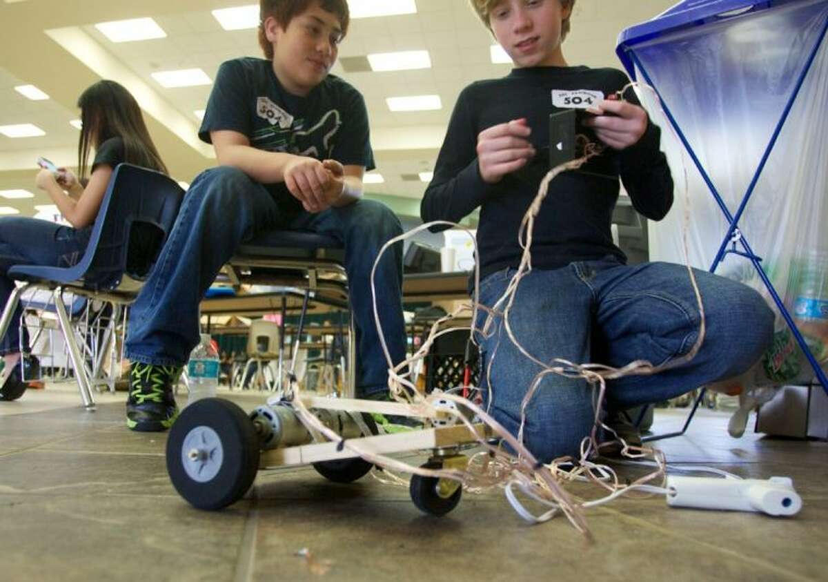 Keaton McGuirk, right, a seventh-grader, works on his robot before competing in Saturday’s SCI://TECH Engineering Design Competition at Moorhead Junior High.