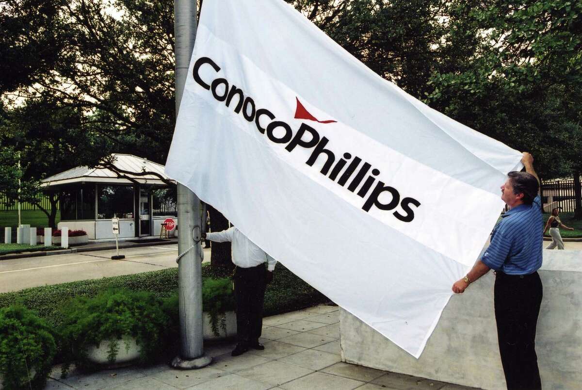 A ConocoPhillips worker raises the flag at the new company's headquarters after the 2002 merger.