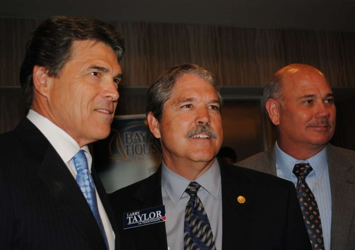 Texas Gov. Rick Perry, left, looks out at the sellout crowd that came to hear him at the Clear Lake Hilton Monday with State Rep. Larry Taylor, center, and Bay Area Houston Economic Partnership President Bob Mitchell.