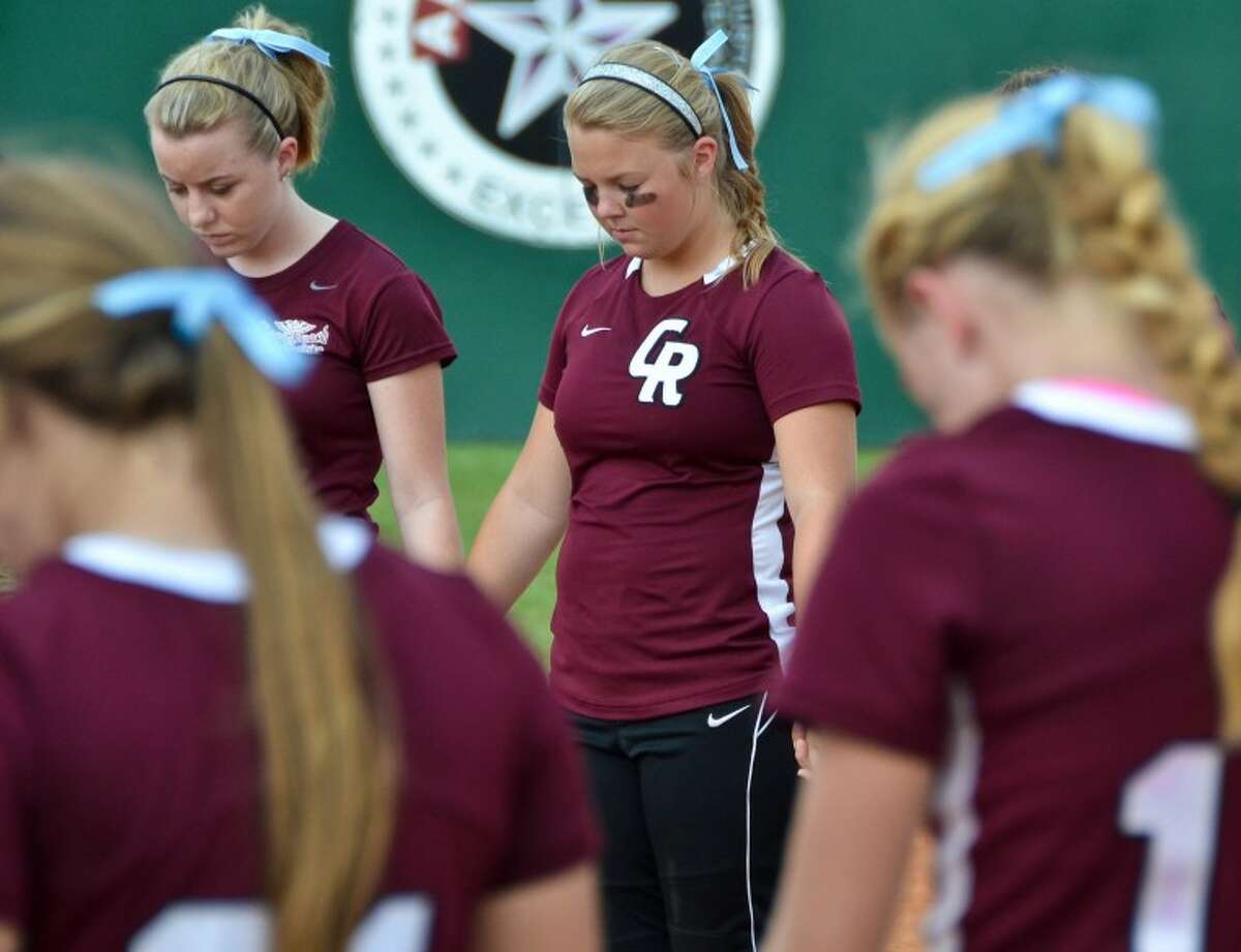 Cinco Ranch softball players gather in a prayer circle before the start of an area playoff game against Aldine MacArthur May 5. The prayer circle was in memory of umpire Ricky Scearce, Jr., a Katy resident who died of a heart attack on the field during a game between the two teams the night before.