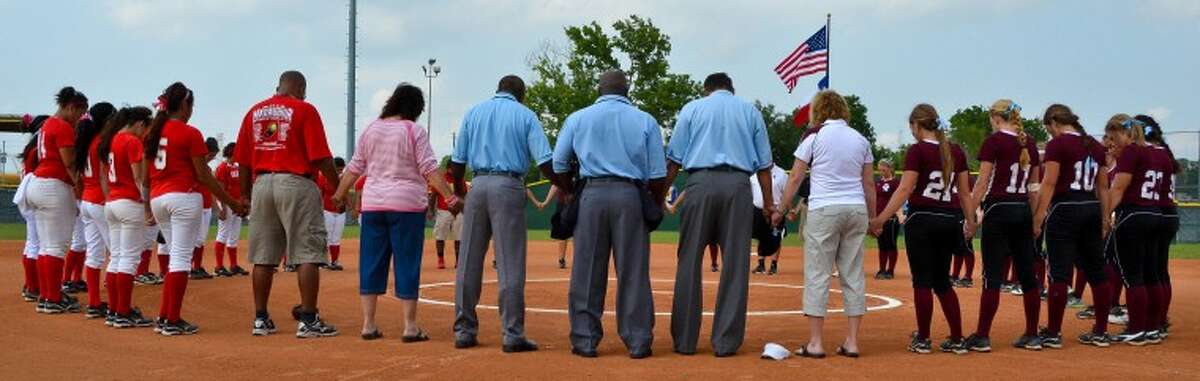 Umpires, players and district officials from both Aldine ISD and Katy ISD gather in a prayer circle before the start of an area playoff game between Cinco Ranch and Aldine MacArthur May 5. The prayer circle was in memory of umpire Ricky Scearce, Jr., a Katy resident who died of a heart attack on the field during a game between the two teams the night before.