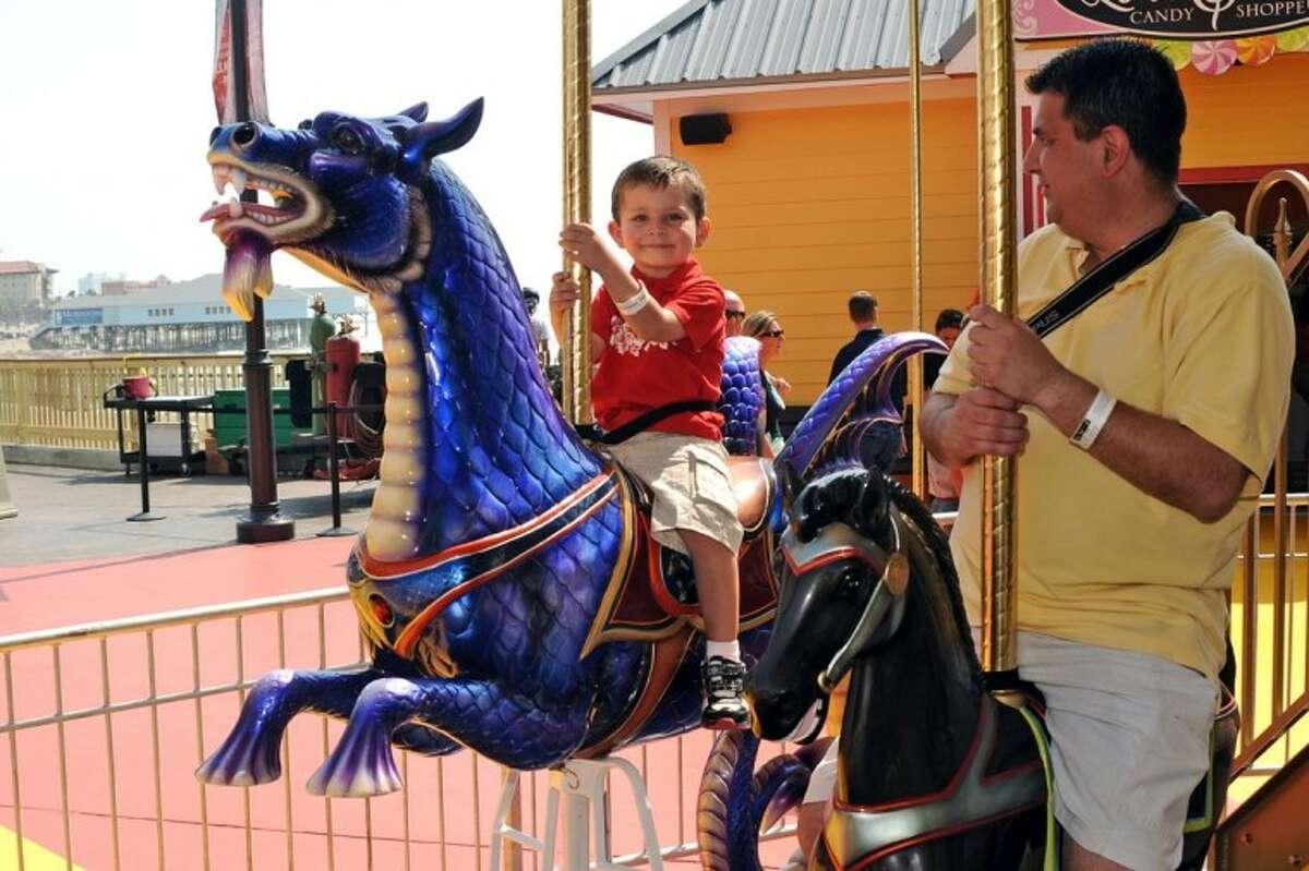 James Gonzalez and Jaime Gonzalez enjoy a ride on the Carousel as the Galveston Island Historic Pleasure Pier opens on the Seawall in Galveston Friday, May 25.