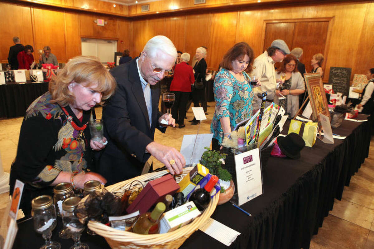 Jacqueline and Chuck Bertrand of Pecan Grove look over a wine basket for the silent auction at the Reading between the Wines at Safari Texas put on by the Literacy Council of Fort Bend County in Richmond. (Photo by Alan Warren)