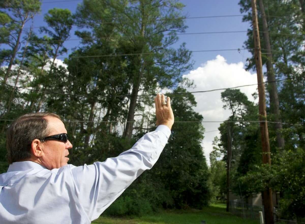 Tim Sbrusch, Service Area Director for CenterPoint Energy, points out power lines near trees.
