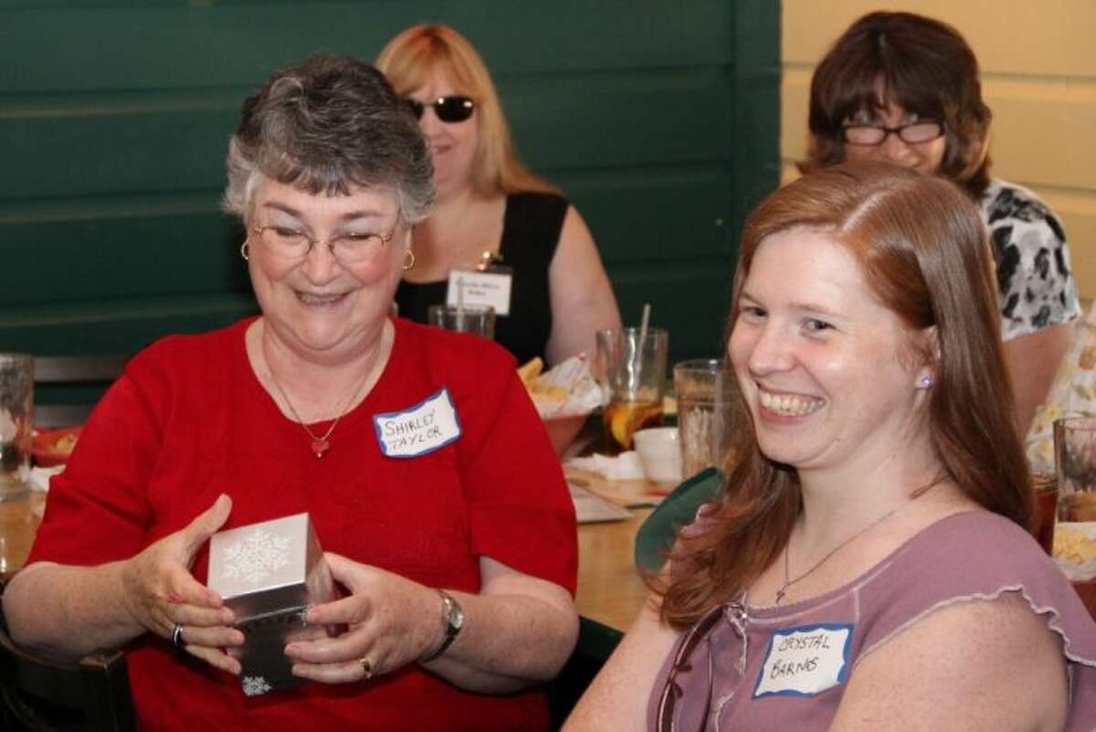 Author Shirley Taylor smiles as she receives the door prize during the July meeting of Writers on the Storm Saturday. She is seated next to Author Crystal Barnes.