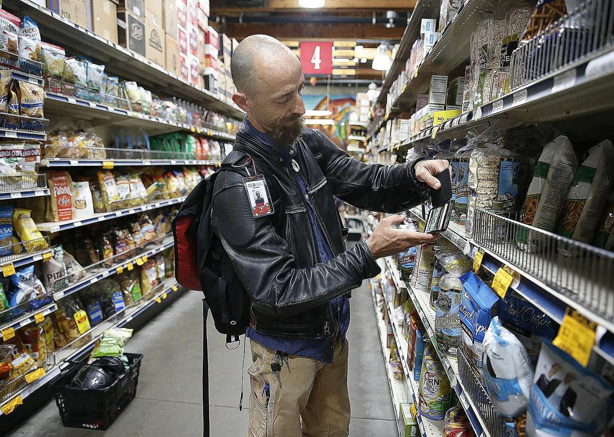 Customer David Skolnick tries to scan items on the Selfycart app at Rainbow in San Francisco.