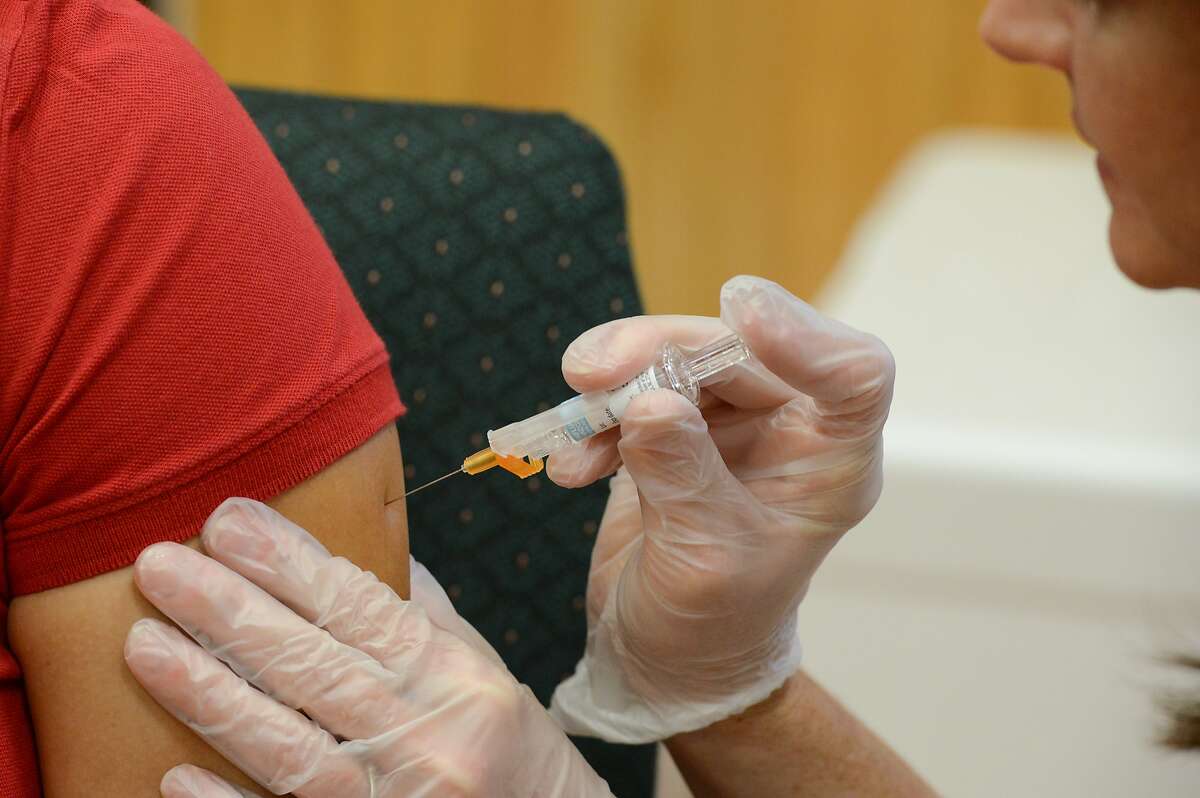 In a Friday, Sept. 16, 2016 photo, a woman receives a flu vaccine shot, at a community fair in Brownsville, Texas. Vouchers were provided for many participants at the fair, eliminating the cost associated with the annual vaccination. (Jason Hoekema/The Brownsville Herald via AP)