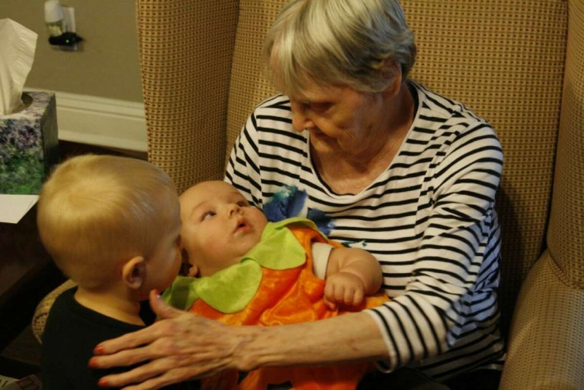 One of the seniors at Unlimited Care-Kingwood Cottage spends time with two members of the Baby Buddies during their holiday celebration Oct. 3.