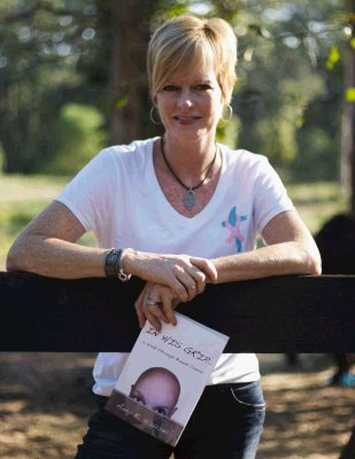 Breast cancer survivor Amy Hauser holds a copy of her book "In His Grip ... A Walk Through Breast Cancer." Hauser runs the ministry Horses-Healing-Hope., which provides equine therapy for women who are post-treatment for breast cancer.