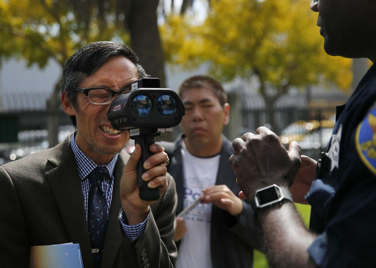 Richmond District Supervisor Eric Mar, left, looks into a LIDAR device of Police Officer Leroy Thomas, right, used to measure speeding cars after a press conference at the Gene Friend Rec Center Sept. 29, 2016 in San Francisco, Calif. SFPD along with SFMTA and Vision Zero announced a renewed effort to catch city speeders by the SFPD.