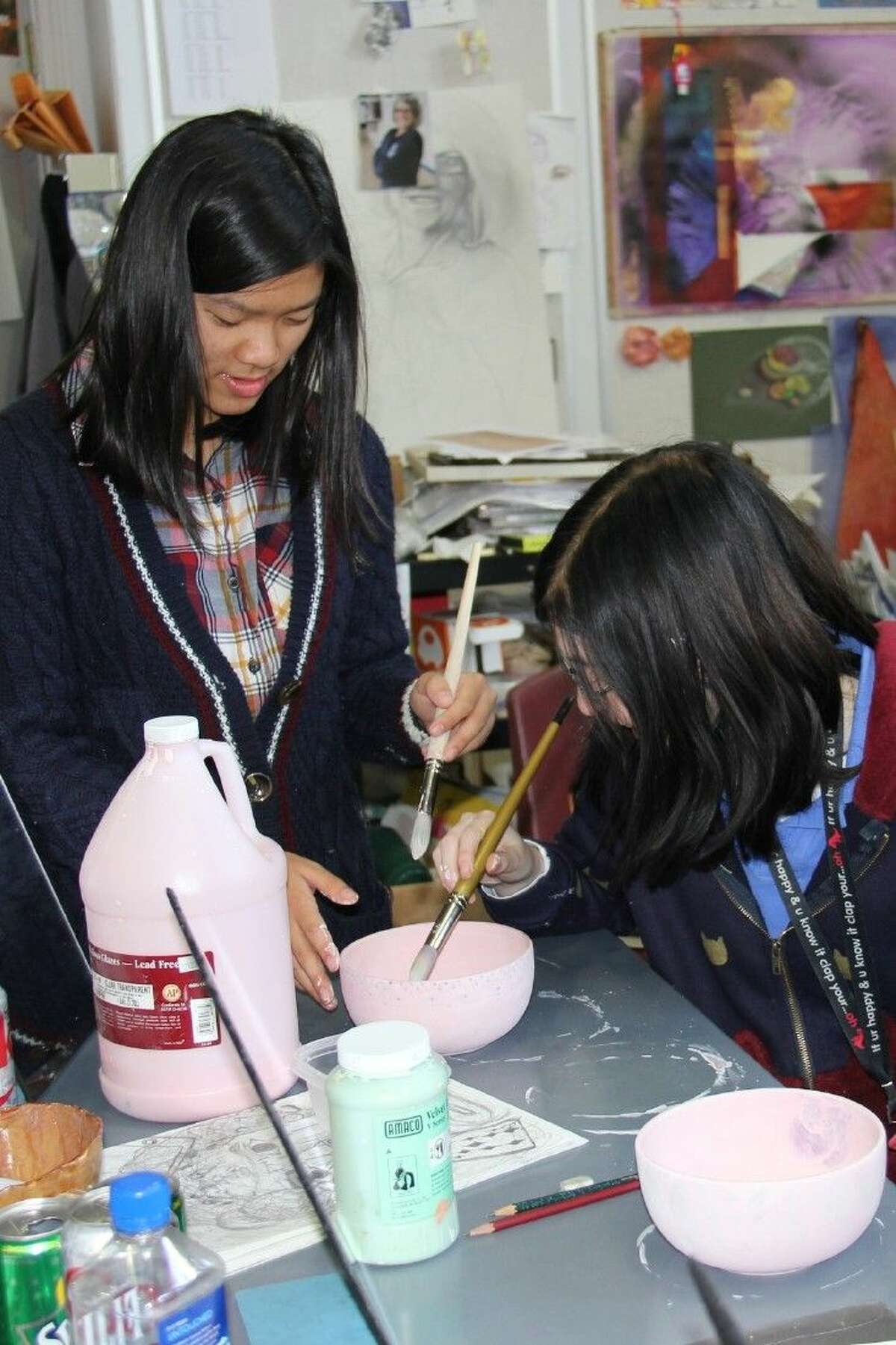 The John Cooper School seniors Meiya Cho and Haley Kent finish up some painting of a handmade bowl, which will be given away as part of the Empty Bowls Project fundraiser for the Interfaith Food Pantry on Saturday.
