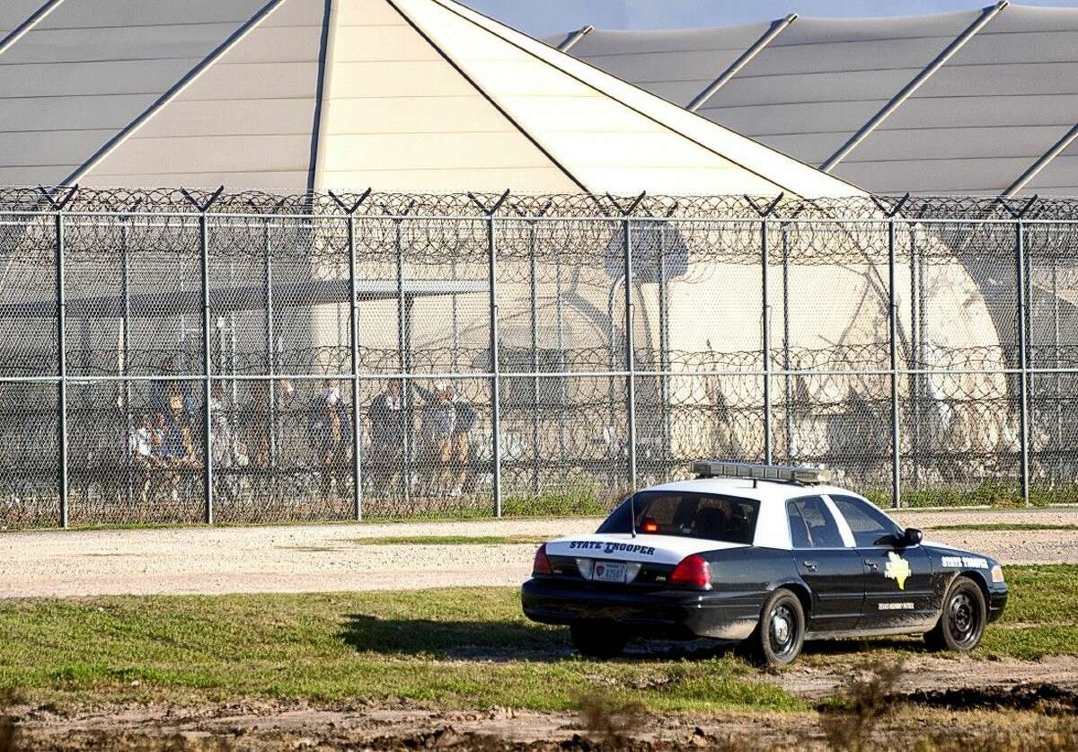 Prisoners on Friday stand at the western fence as law enforcement officials converge on the Willacy County Correctional Center in Raymondville after a prisoner uprising at the private immigration detention center.