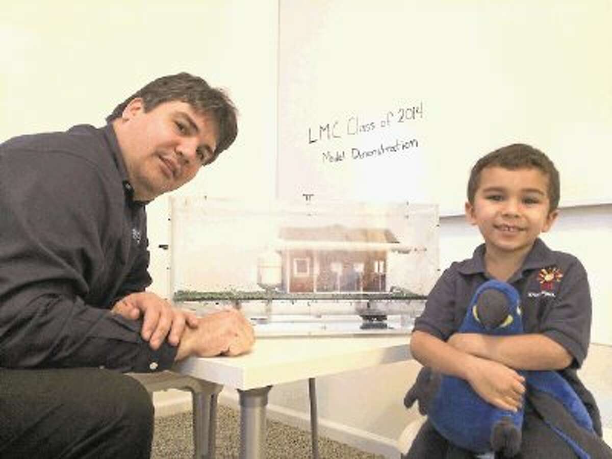 David Matos, with the Leadership Montgomery County Class of 2014, with his son Victor, show off the rainwater harvesting model the class is using as part of the educational tools to go with the class project of building rainwater harvesting systems at Bear Branch Sports Complex in The Woodlands, Oak Ridge Elementary and the North Montgomery County Community Center in Willis.