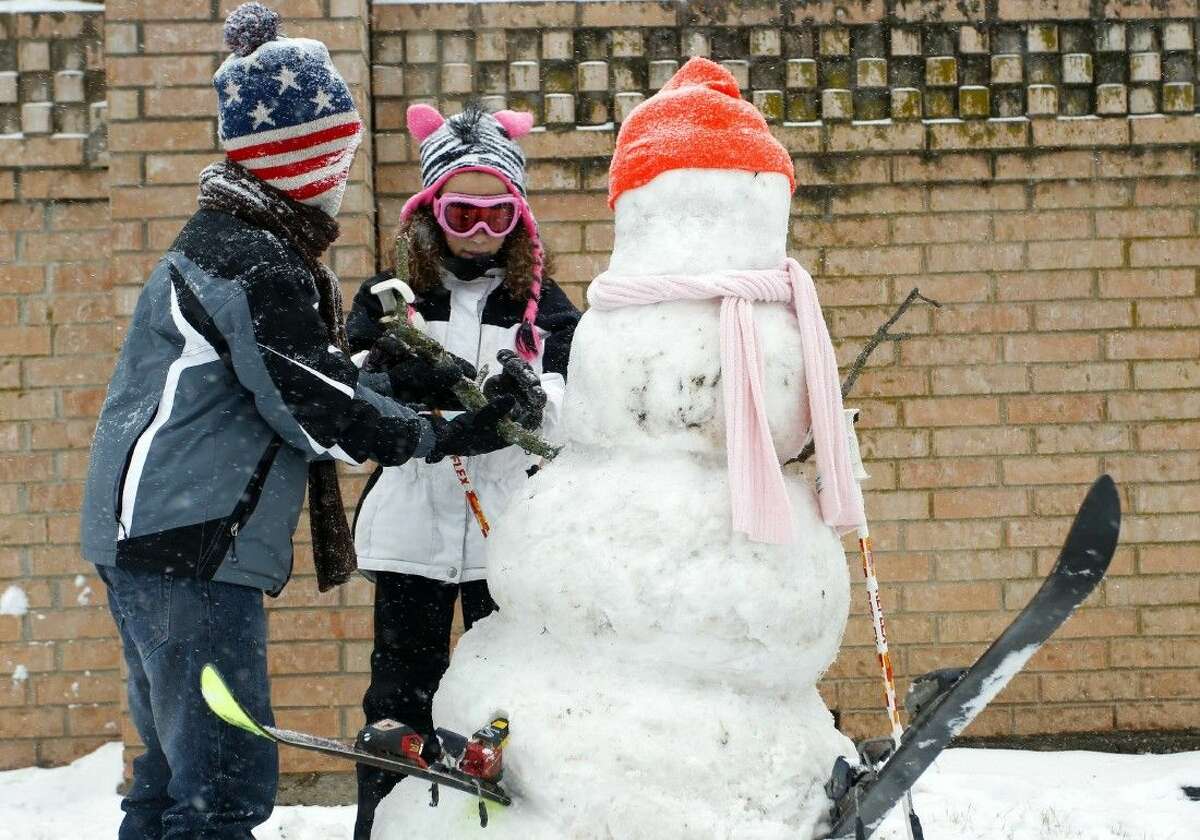 Siblings David and Celine Terry on Friday decorate the snowman they built along Glade Road in Colleyville.