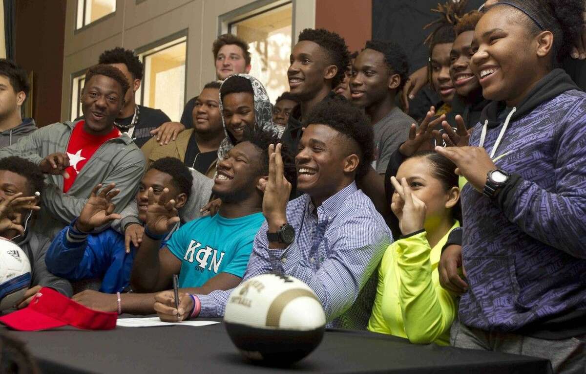 Conroe football player Kamaran Williams, center, poses for a photo along side Daylon Jefferson, left of Williams, during a signing day ceremony at Conroe High School Wednesday. Jefferson, who signed to play football for Kilgore College, joined Williams, signed with Trinity Valley, and five other athletes in signing National Letters of Intent to play various sports at the college level.