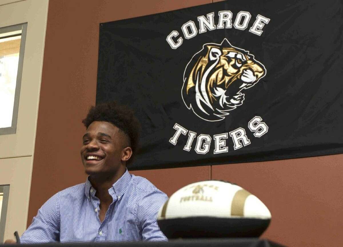 Conroe football player Kameron Williams laughs as he signs a National Letter of Intend to play football for Trinity Valley during a signing day ceremony at Conroe High School Wednesday. Williams joined six other athletes in signing letter to play various sports at the college level.