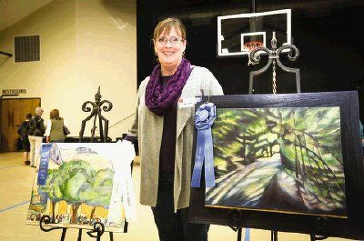The Woodlands artist Julie Graham poses for a portrait with her best of show and best of landscape paintings during the Spring Judged Art Show hosted by the Conroe Art League Saturday at First Baptist Church of Conroe.