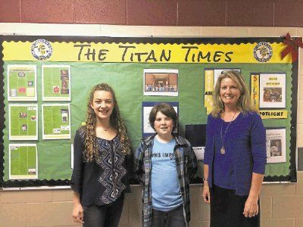 Sixth graders and co-editors-in-chief Payton Gwynne and Mercer Sadlier stand with newspaper advisor Melissa Kilway in front of the Titan Times bulletin board at Coulson Tough Elementary. A new issue of the Titan Times comes out every month.