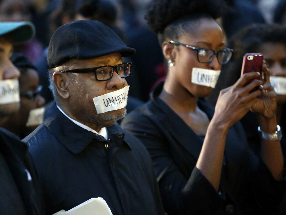 George Henderson, left, professor emeritus, joins students at the University of Oklahoma to protest a fraternity's racist comments on Monday in Norman, Okla. University President David Boren lambasted members of Sigma Alpha Epsilon fraternity on Monday who participated in a racist chant caught on video, calling them disgraceful and their behavior reprehensible, and ordered that their house be vacated by midnight Tuesday.