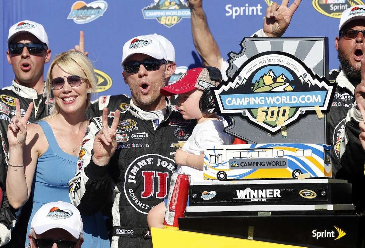 Kevin Harvick poses with his wife DeLana, left, and son Keelan, after winning the NASCAR Sprint Cup Series auto race in Avondale, Ariz.