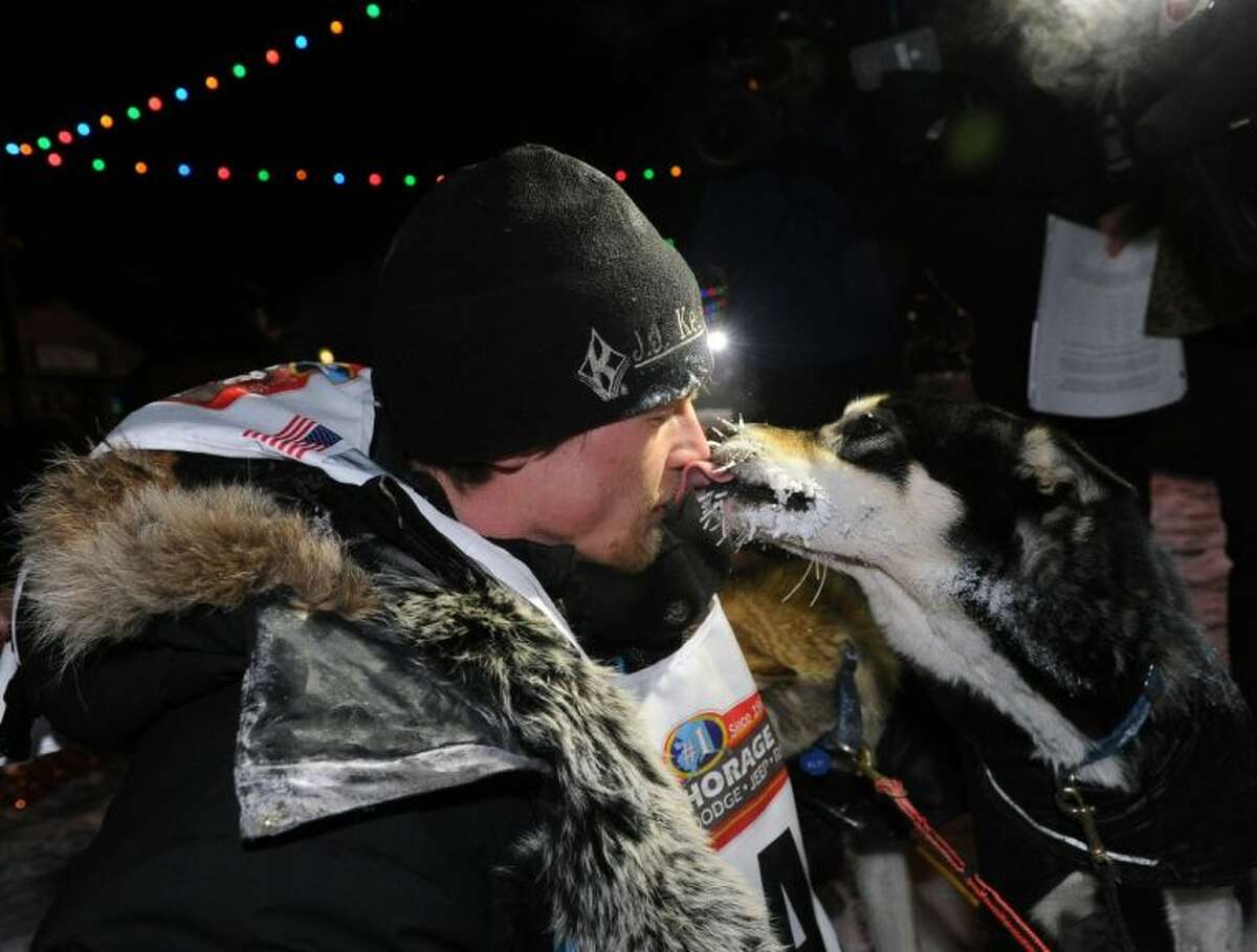 Dallas Seavey gets a kiss from one of his dogs after winning the Iditarod Trail Sled Dog Race on Tuesday in Nome, Alaska.