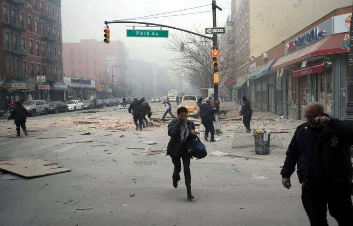 People run after an explosion and building collapse in the East Harlem neighborhood of New York, Wednesday, March 12, 2014. The explosion leveled an apartment building, and sent flames and billowing black smoke above the skyline.