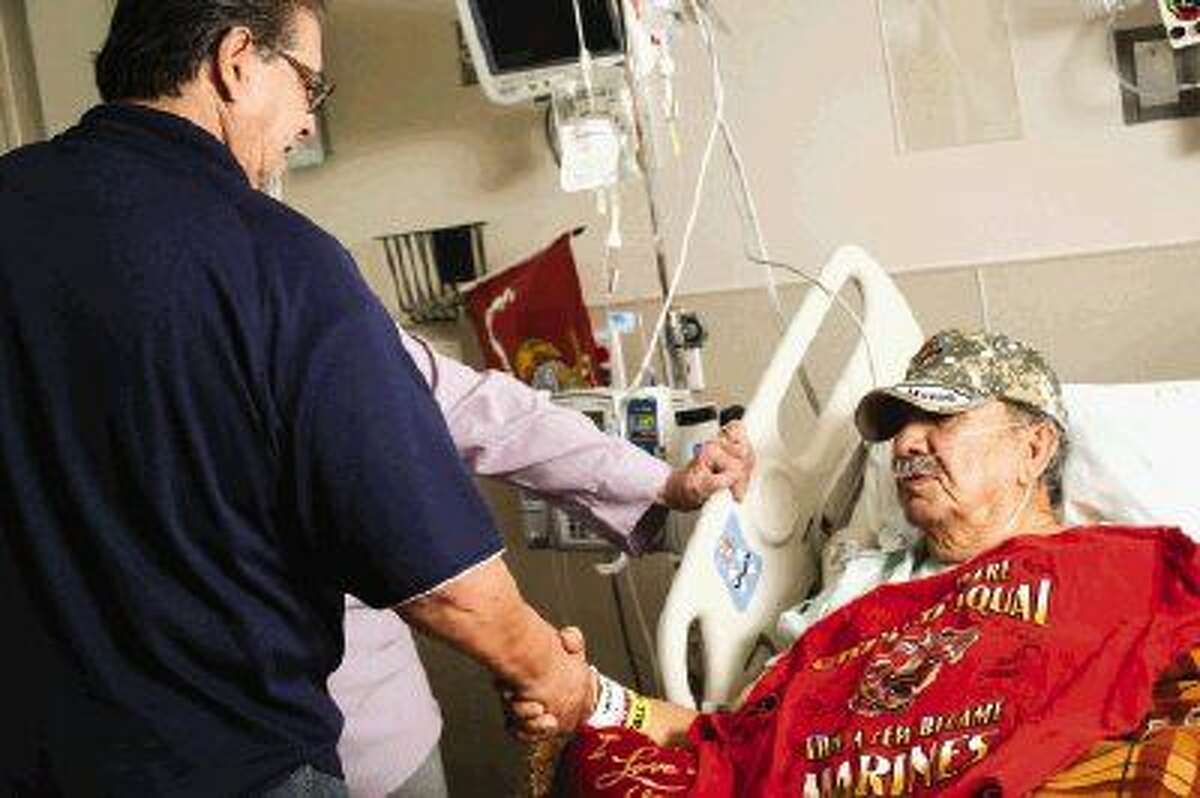 Veteran Bobby Diaz shakes hands with fellow veteran Armando Galarza while recovering from a stroke at Memorial Hermann The Woodlands Hospital.