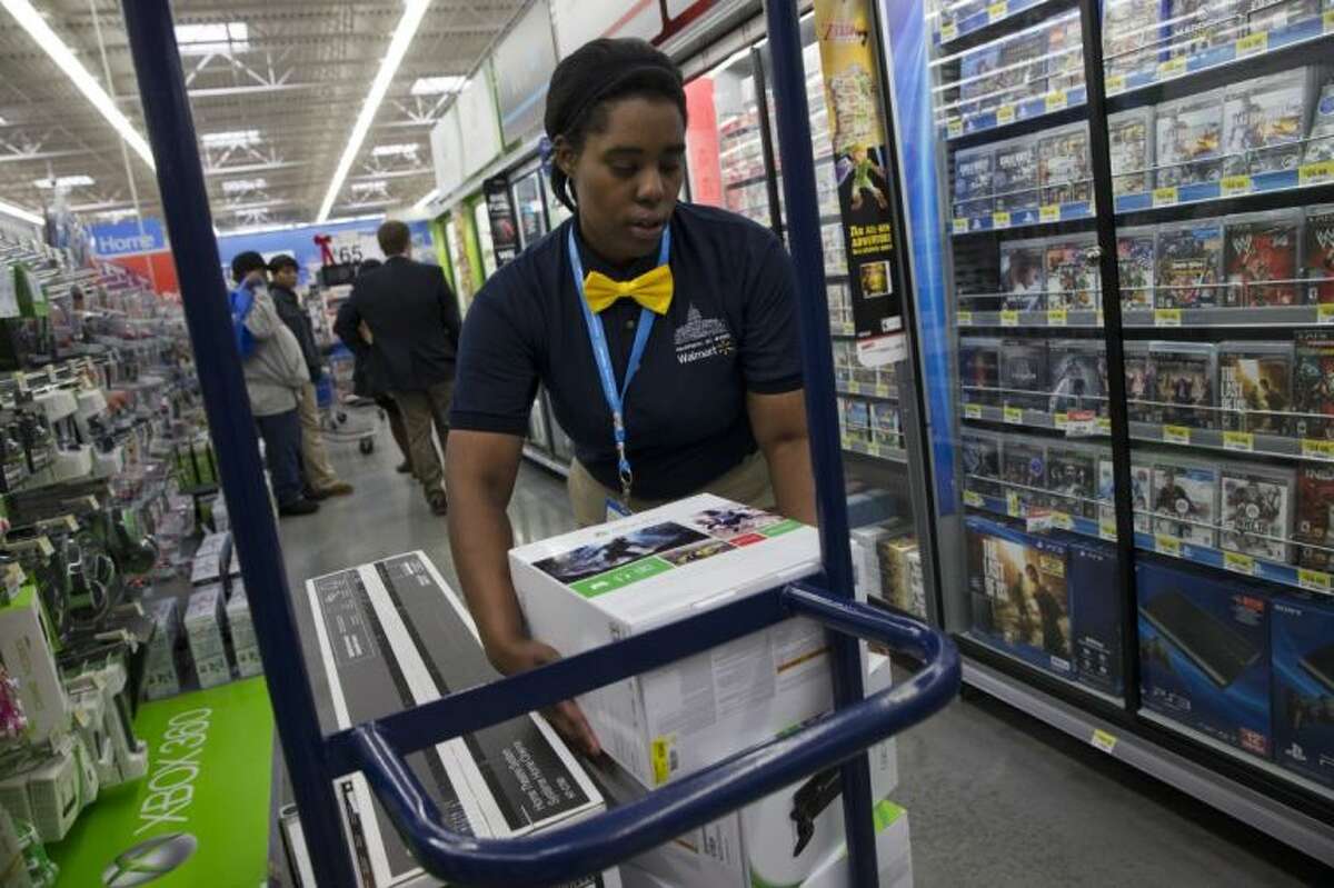 In this Dec. 4, 2013, file photo, Tracey Anderson, 26, re-stocks X-Box sets on opening day of a new Wal-Mart on Georgia Avenue Northwest in Washington. Wal-Mart plans to expand its video game trade-in program to its stores, offering store credit for thousands of video games.