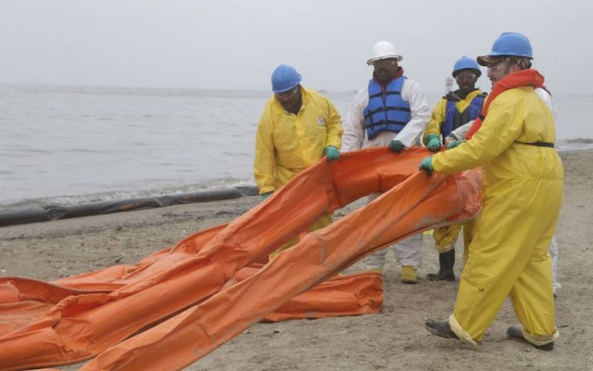 An oil spill clean up crew drags a boom along East Beach in Galveston, Texas, Monday, March 24, 2014. Thousands of gallons of tar-like oil spilled into the major U.S. shipping channel after a barge ran into a ship Saturday.