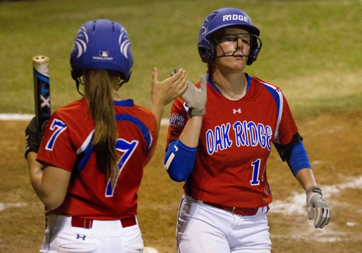 Oak Ridge's Haley Nillen, right, gets a high-five from Kylie Hunt after scoring a run in the third innning during a District 16-6A softball game at Conroe High School Tuesday. Go to HCNpics.com to purchase this photos, and other like it.